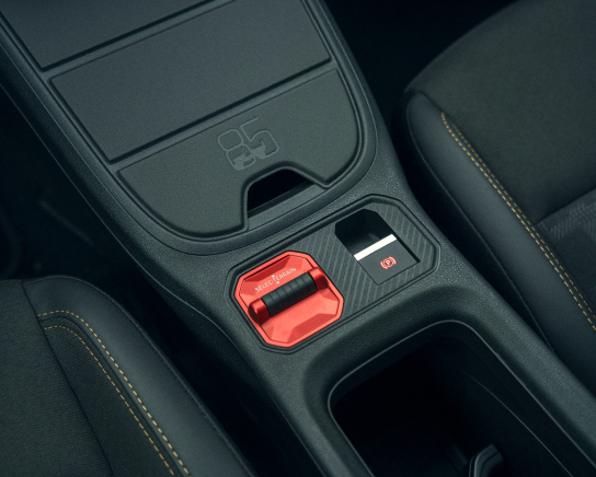Mittelkonsole des Jeep Avenger 4xe mit rotem Fahrmodusregler, elektronischer Parkbremse und Ablagefach.