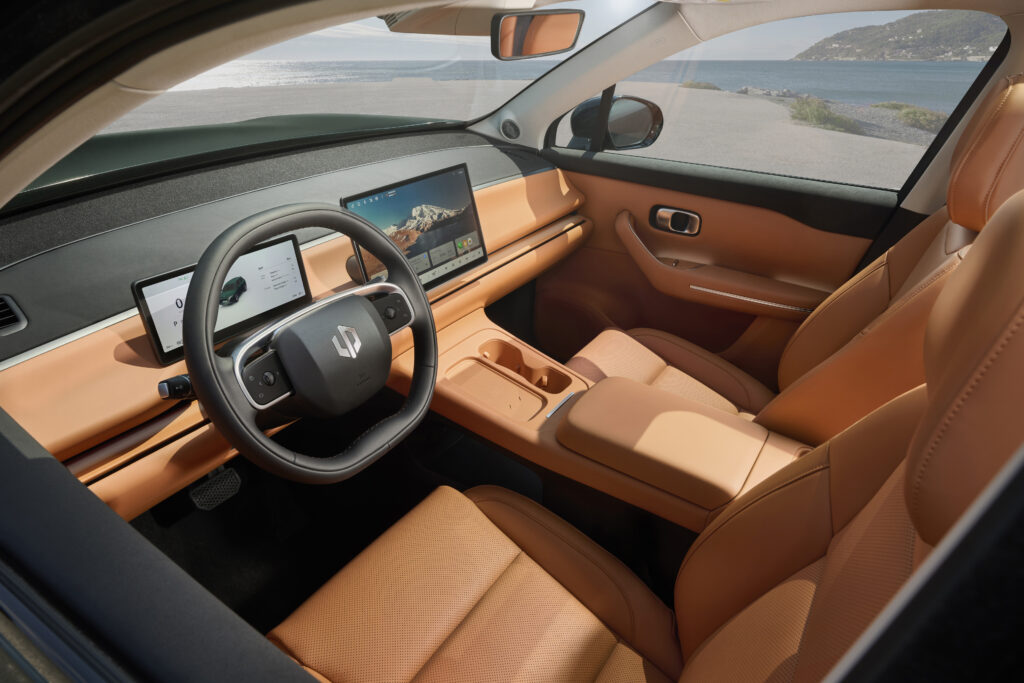 Blick in den orangefarbenen Innenraum des Leapmotor C10 mit Vordersitzen, Lenkrad, digitalen Displays und Mittelkonsole.
